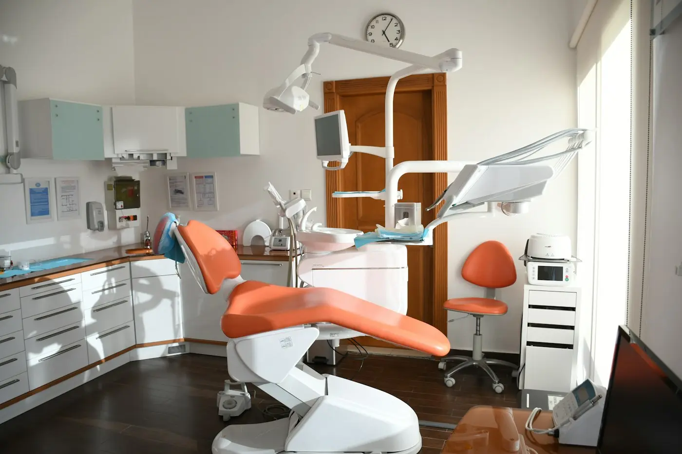 Modern dental treatment room with an orange patient chair
